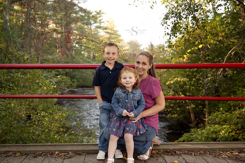 A mother and her young son and daughter pose on the bridge at Fallbrook SUNY Oswego with Simply Shelayna Family Photography in Oswego NY.