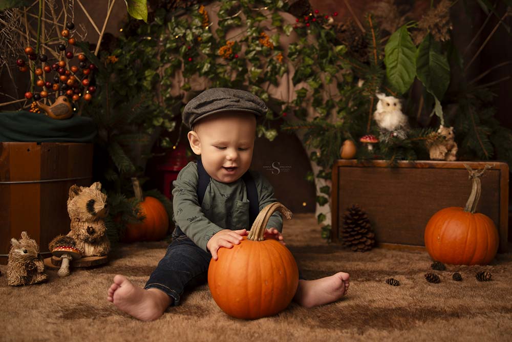 A baby boy in a chapped hat sits for a portrait in a autumn woodland scene with Simply Shelayna Baby Photography in Syracuse NY.A baby boy in a chapped hat sits for a portrait in a autumn woodland scene with Simply Shelayna Baby Photography in Syracuse NY.