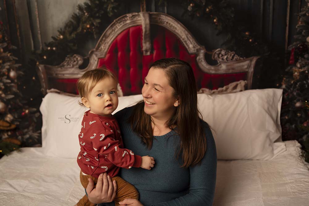 A mother holds her 1 year old son for a Christmas portrait with Simply Shelayna family photography in CNY.