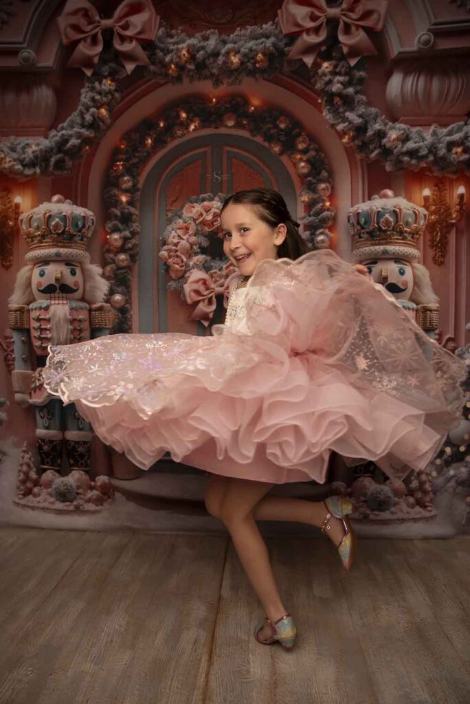 A young girl in a pink nutcracker dress dances with Simply Shelayna Family Photographer in Syracuse NY.