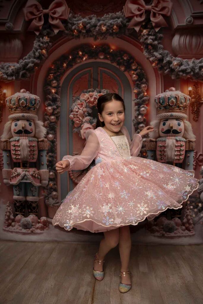 A young girl in a pink nutcracker dress dances with Simply Shelayna Family Photographer in Syracuse NY.