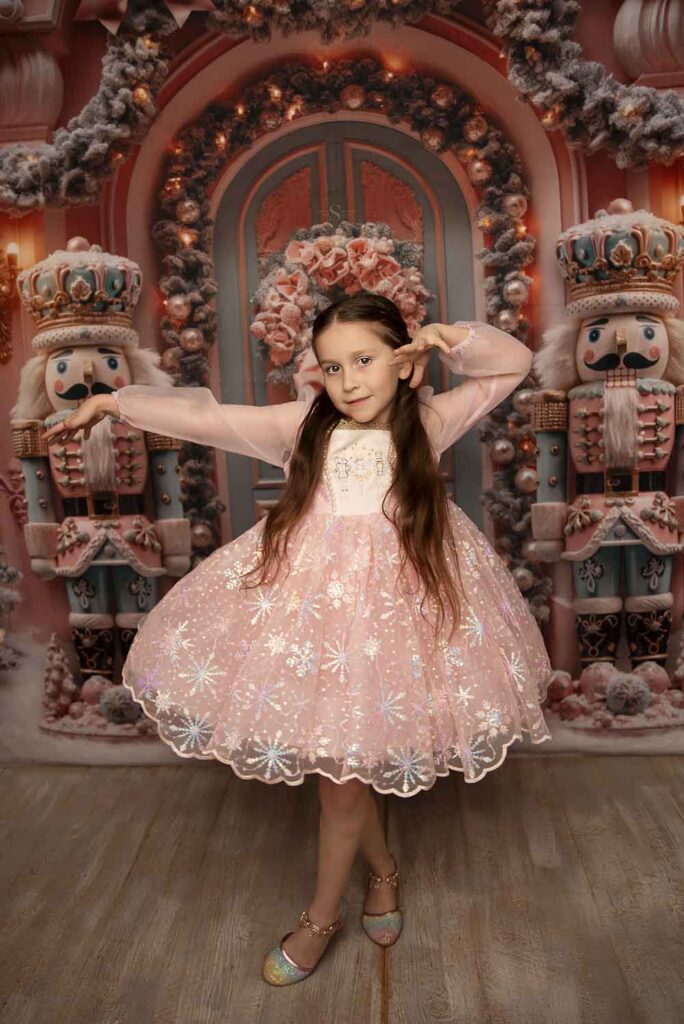 A young girl in a pink nutcracker dress dances with Simply Shelayna Family Photographer in Syracuse NY.