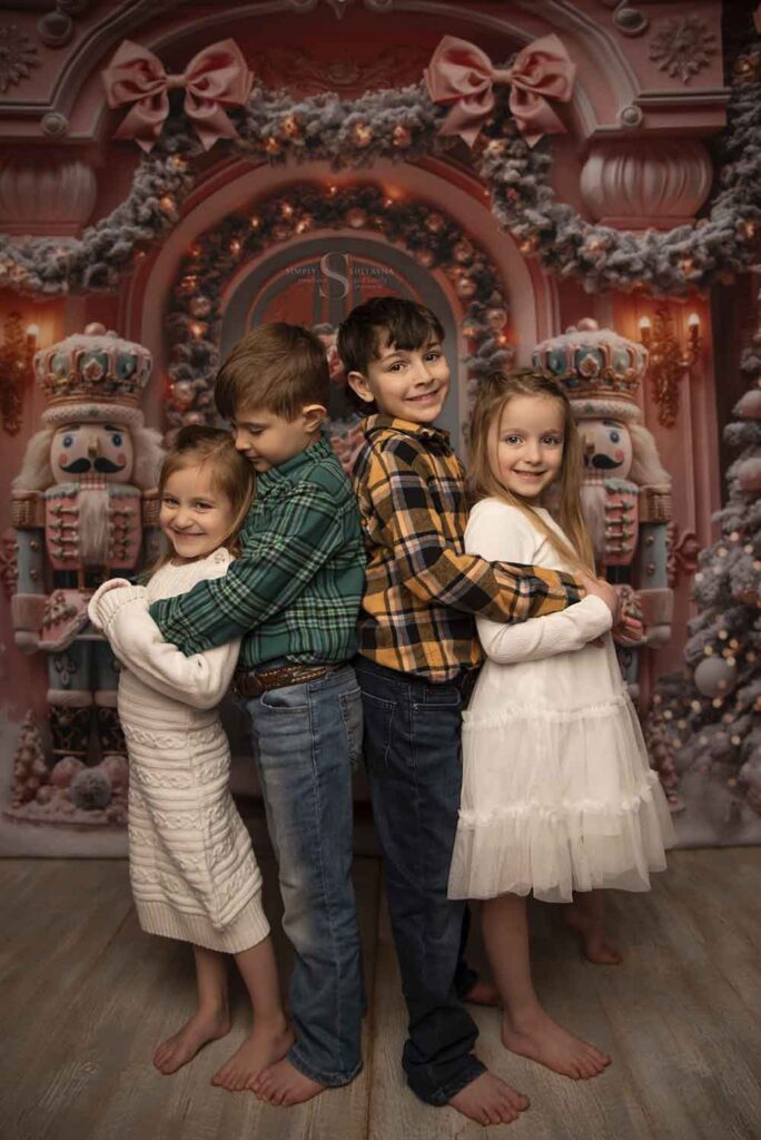 Four siblings, two boys and two girls pose for a portrait with Simply Shelayna Family Photographer in her Limited Edition Christmas portraits in Oswego NY.
