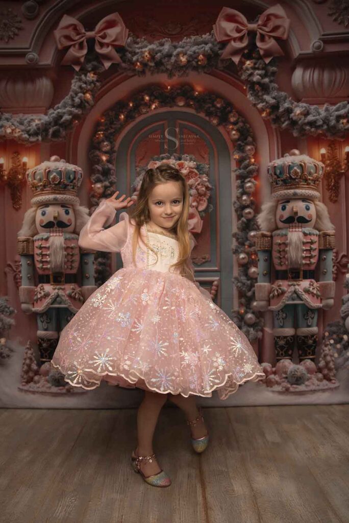 A young girl poses for the camera in a pink nutcracker dress for Christmas portraits with Simply Shelayna Family photography in Syracuse NY.