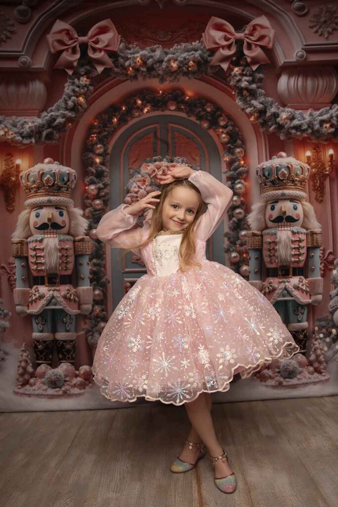 A young girl poses for the camera in a pink nutcracker dress for Christmas portraits with Simply Shelayna Family photography in Syracuse NY.