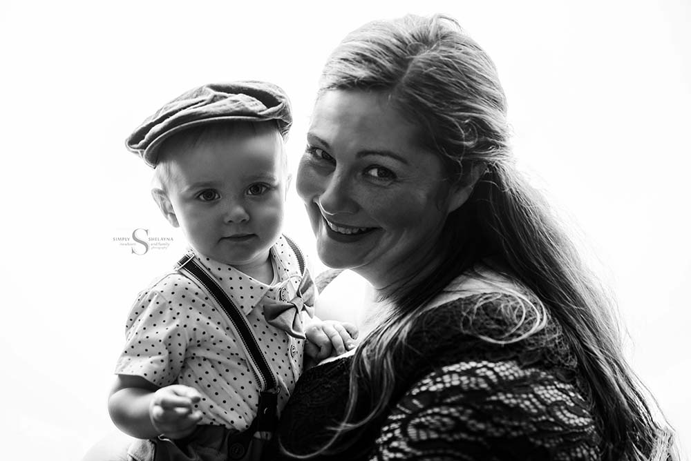 A mother holds her son in a backlit studio black and white portrait with Simply Shelayna Family Photography in Oswego NY.