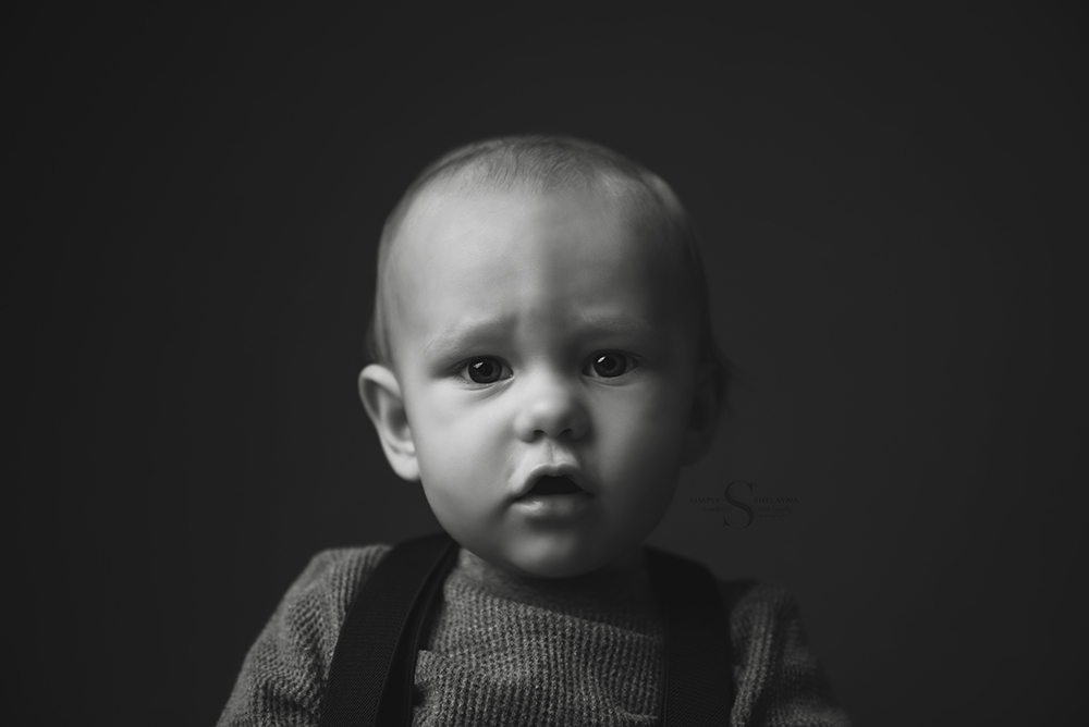 A classic black and white portrait of a baby boy in suspenders with Simply Shelayna infant photography in Oswego NY.