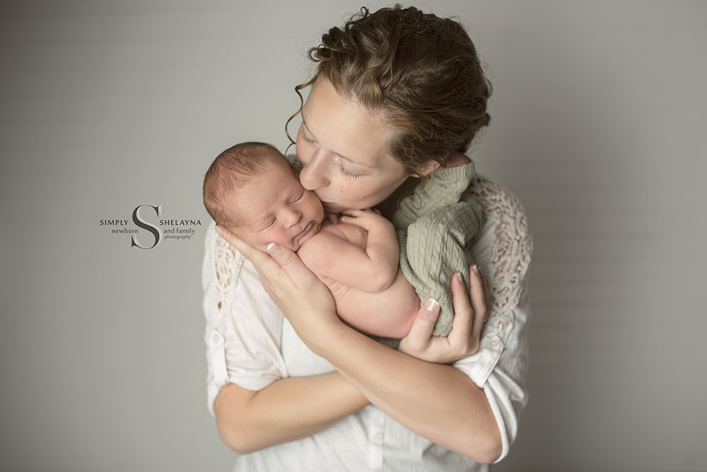 A mother tenderly kisses her newborn son with Simply Shelayna Newborn Photography in Syracuse NY.