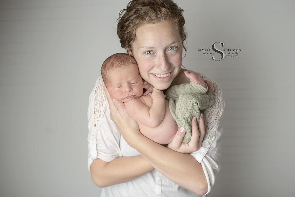 A mother tenderly holds her newborn son with Simply Shelayna Newborn Photography in Syracuse NY.