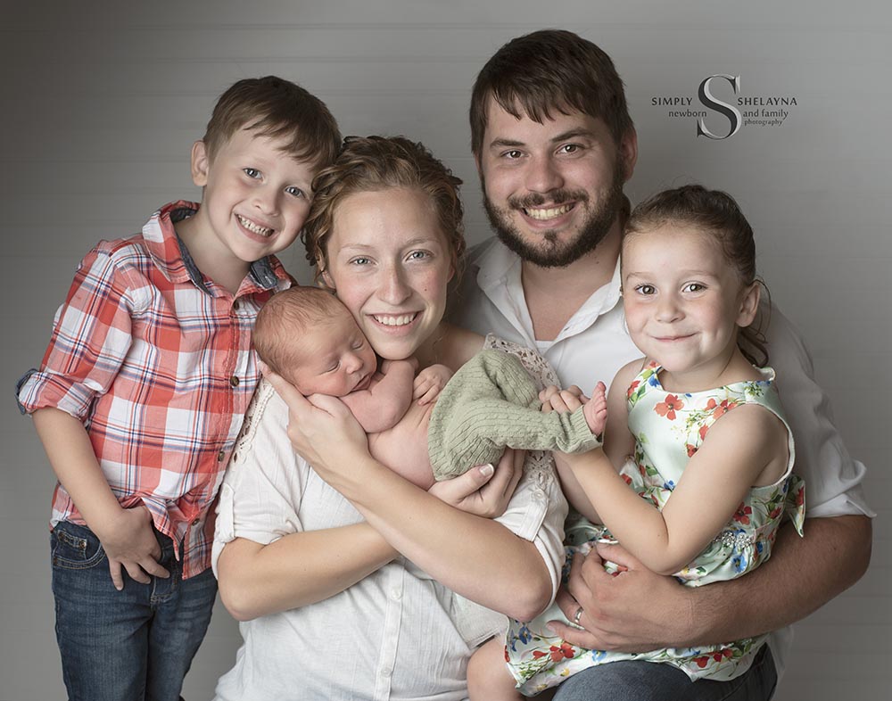 A family of five poses for a portrait with their newborn baby in Syracuse NY with Simply Shelayna Newborn photography.