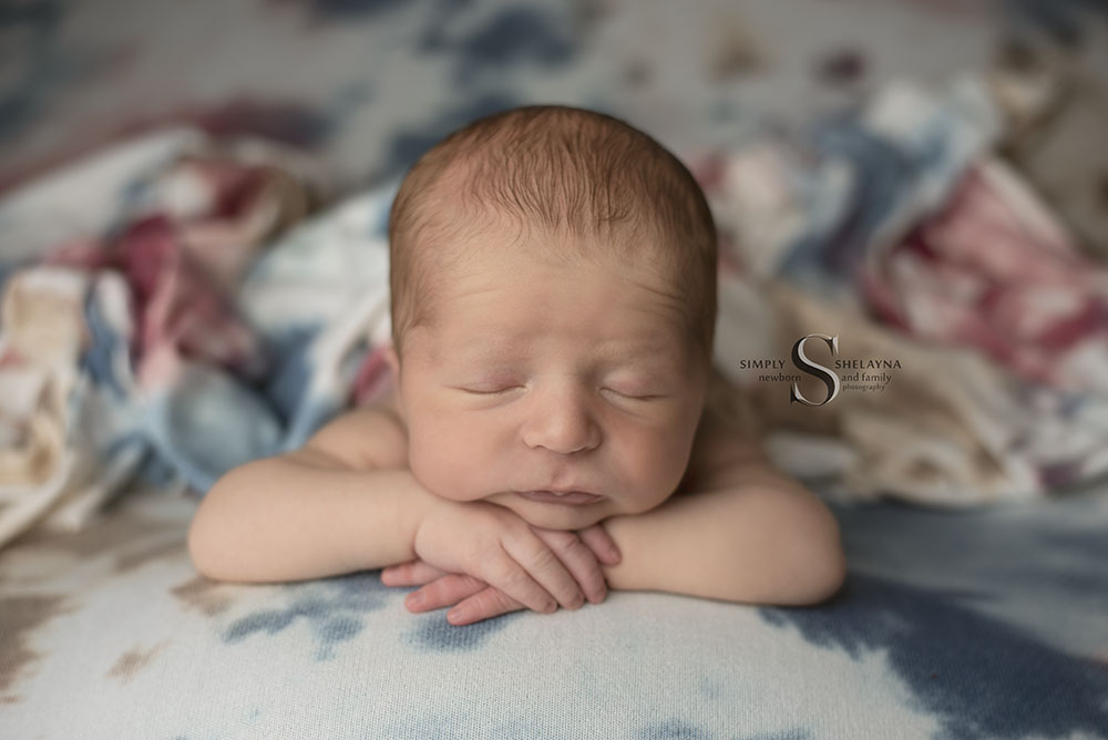A newborn baby boy is posed chin up with Simply Shelayna Photography in CNY.