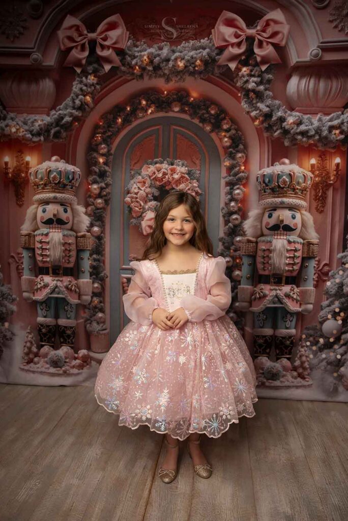 A young girl wears a pink Christmas nutcracker gown for a Christmas portrait with Simply Shelayna Family Photography in Oswego NY.