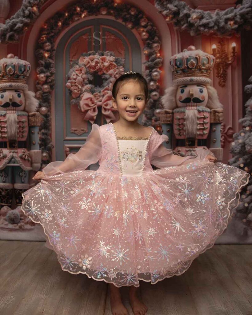 A toddler girl flares out her ballgown dress for a Christmas portrait with Simply Shelayna Photography in CNY.