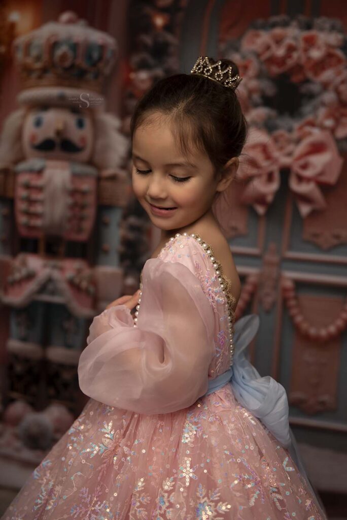 A little girl looks over her shoulder for a Christmas portrait with Simply Shelayna Family Photography in CNY.