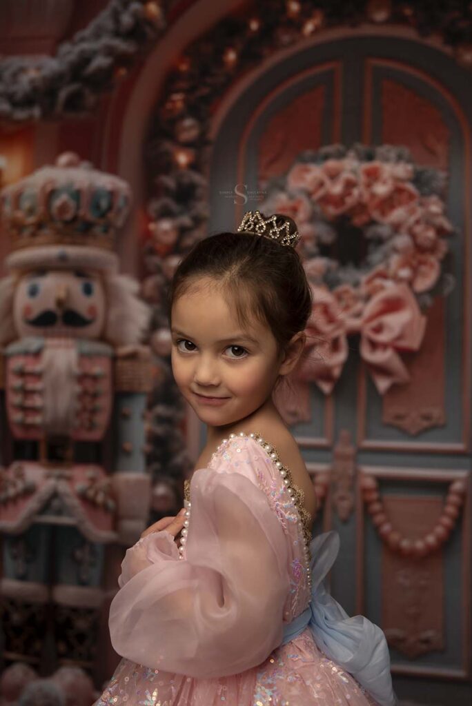 A little girl looks over her shoulder for a Christmas portrait with Simply Shelayna Family Photography in CNY.