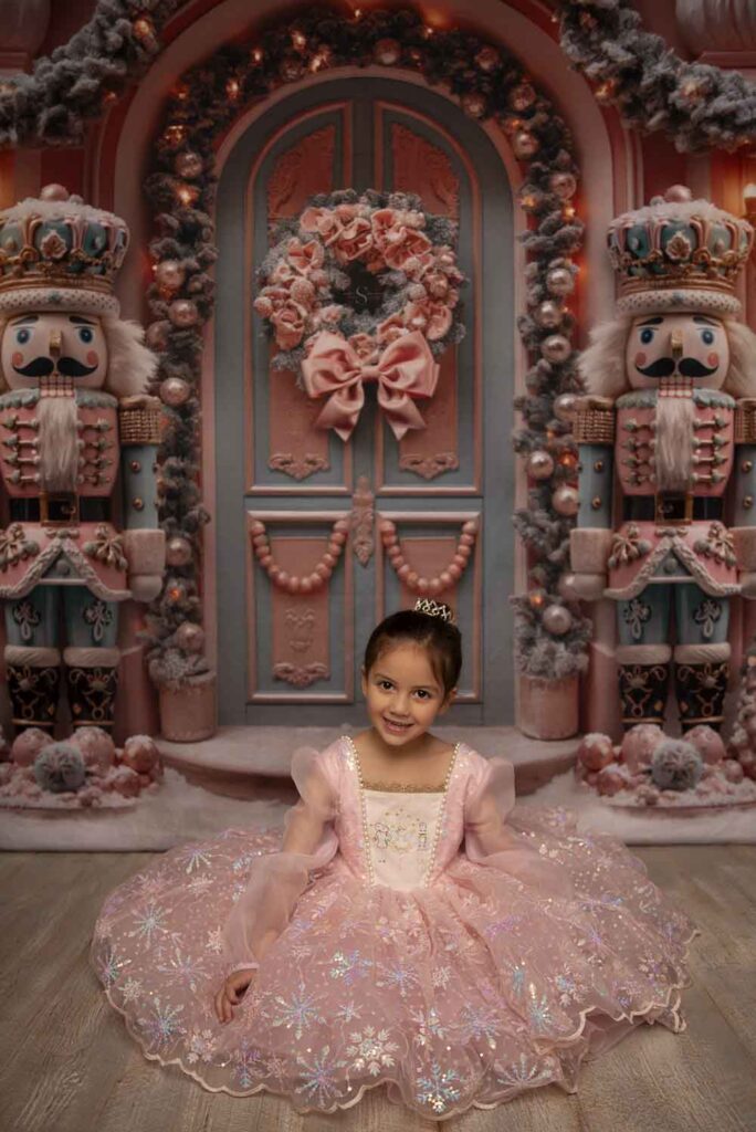 A young girl sits on the floor in a pink ballgown with it fluffed all around her for a Christmas portrait with Simply Shelayna Family Photography in Syracuse NY.