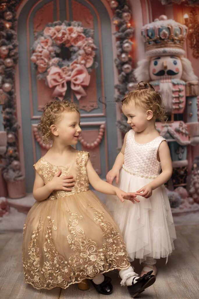 Two sisters pose in Christmas dressed for a portrait with Simply Shelayna Christmas Photography in Albany NY.