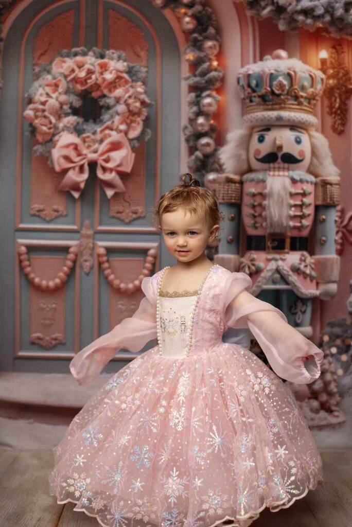 A young girl poses in a pink Nutcracker Christmas dress for a portrait with Simply Shelayna Photography in Albany NY.