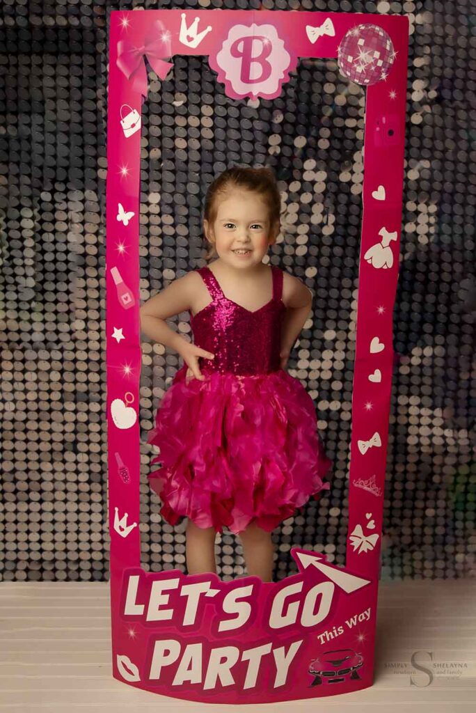 A young girl dressed like Barbie stands in a display box with Simply Shelayna Photography in Syracuse NY.