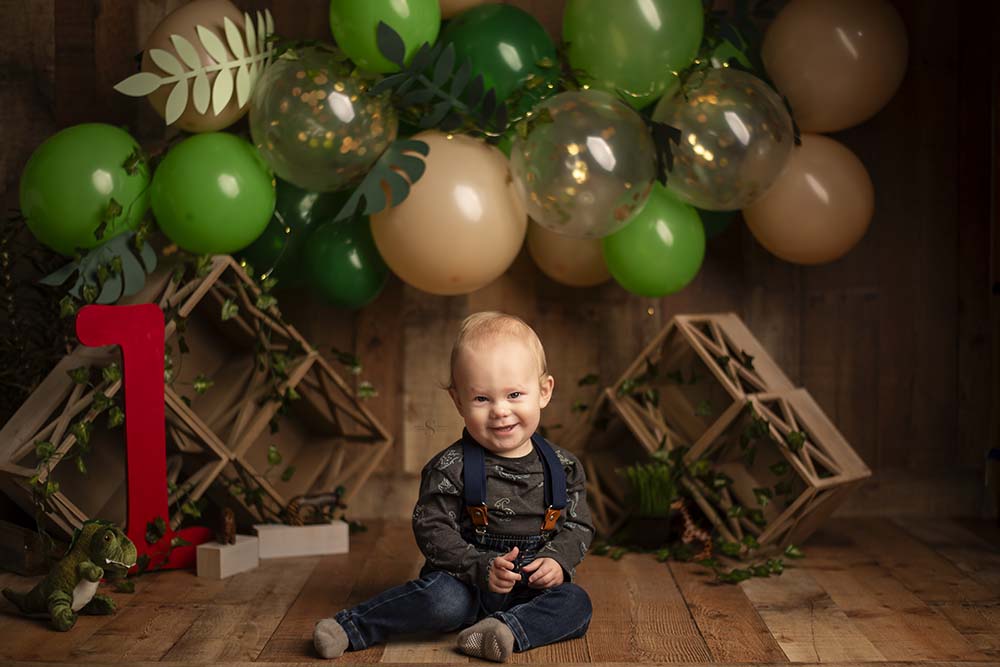 A one year old baby sits in a balloon jungle setting with Simply Shelayna baby photography in CNY.