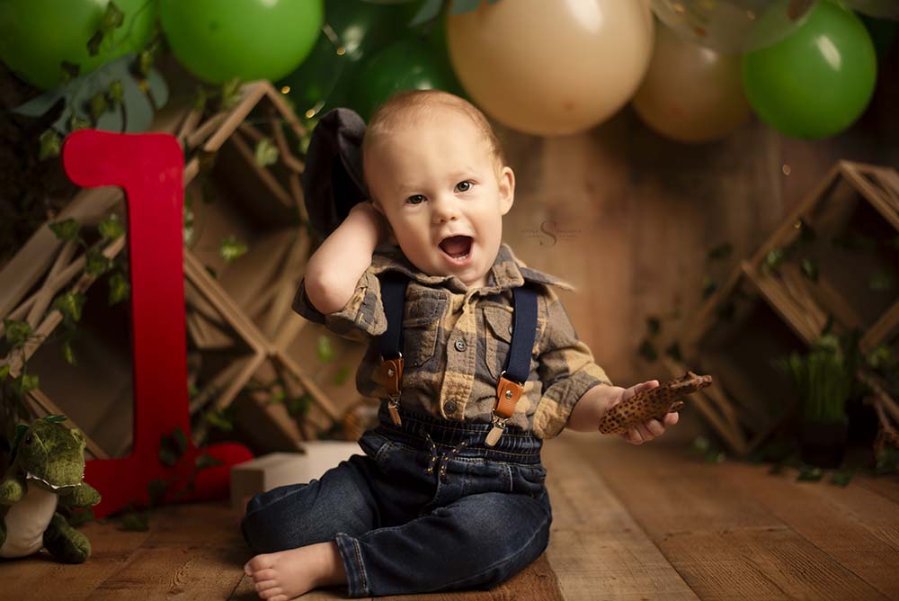 With a surprised look, a baby boy is captured during his first birthday portrait session with Simply Shelayna Milestone photography in Oswego NY.
