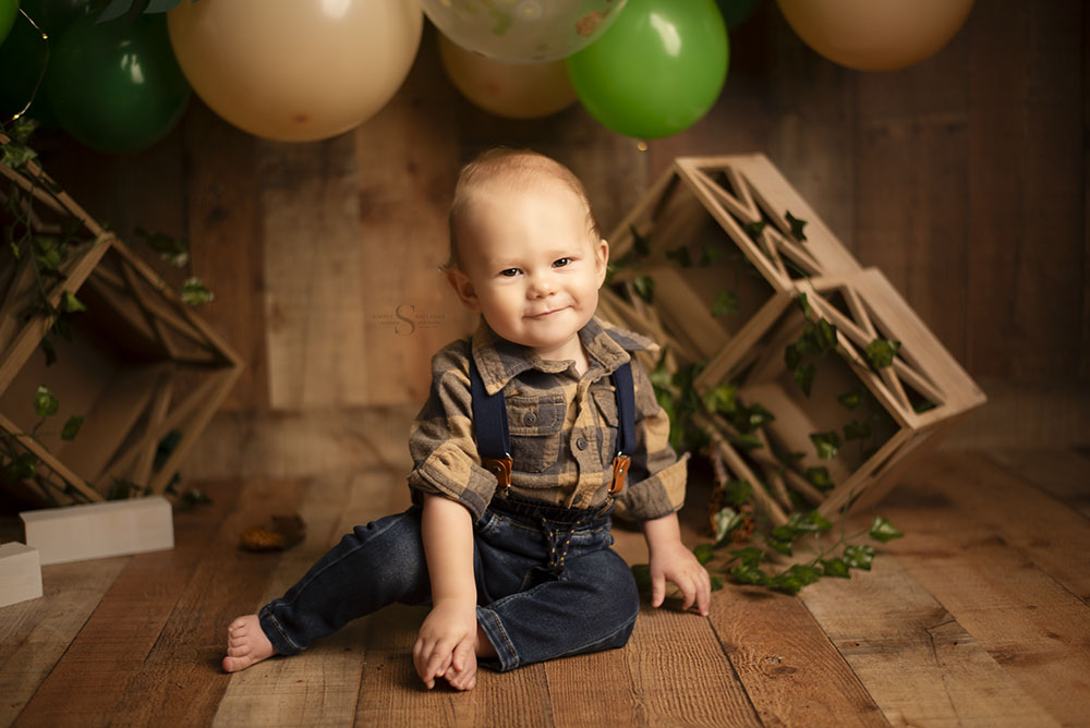 With a crafty grin, and 1 year old boy smirks for a portrait with Simply Shelayna Baby Photography in Oswego NY.