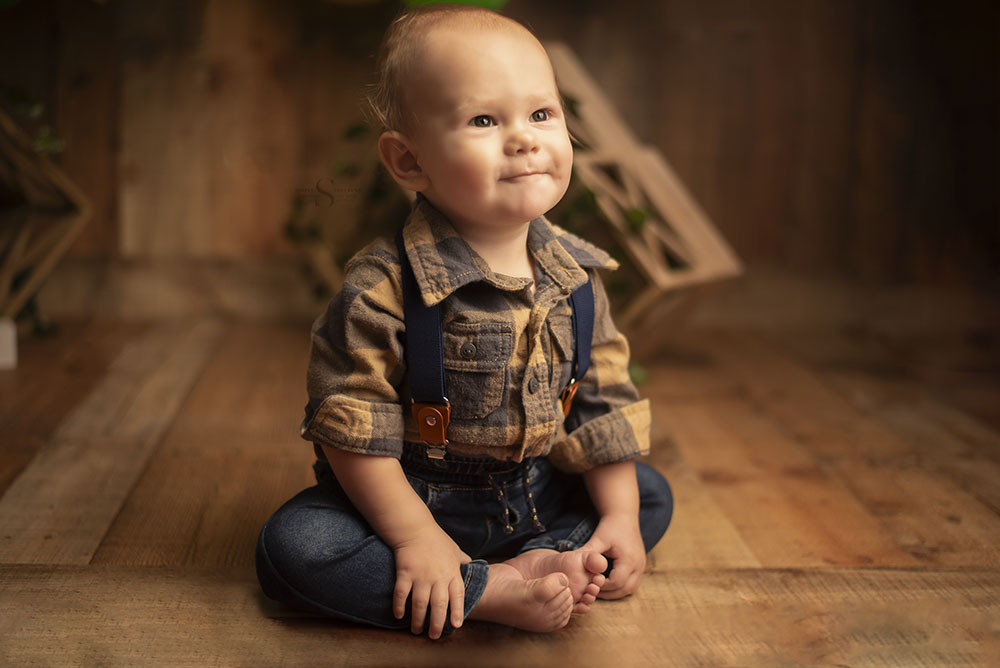 A one year old boy bum shuffles across the studio as a mode of transportation with Simply Shelayna Milestone photography in Syracuse NY.