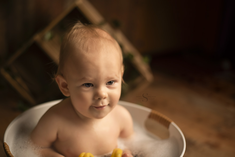 A one year old boy enjoys a bubble bath splash with Simply Shelayna Baby photography in CNY.