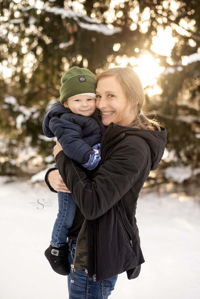 A mother holds close her one year old sun in a glowing snow theme with Simply Shelayna Family Photographer in Oswego NY.