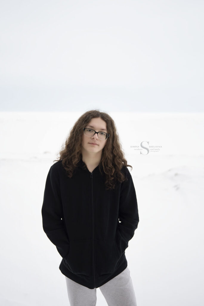 With Lake Ontario as an epic frozen backdrop, a young man poses for high school senior portraits with Simply Shelayna in Oswego NY.