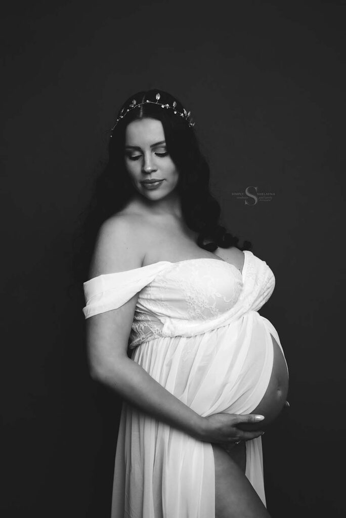 An expectant mother holds her baby bump for a black and white glamour portrait with Simply Shelayna maternity and newborn photography in Syracuse NY.