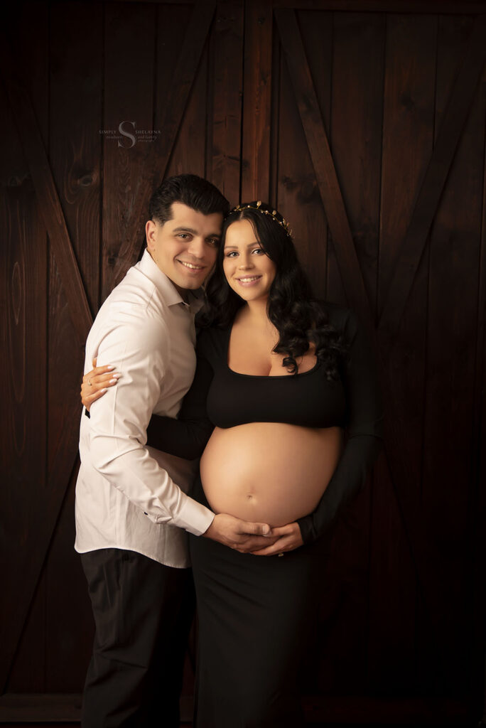 A couple hold each other close for a maternity portrait with Simply Shelayna Maternity Photography in Oswego NY.