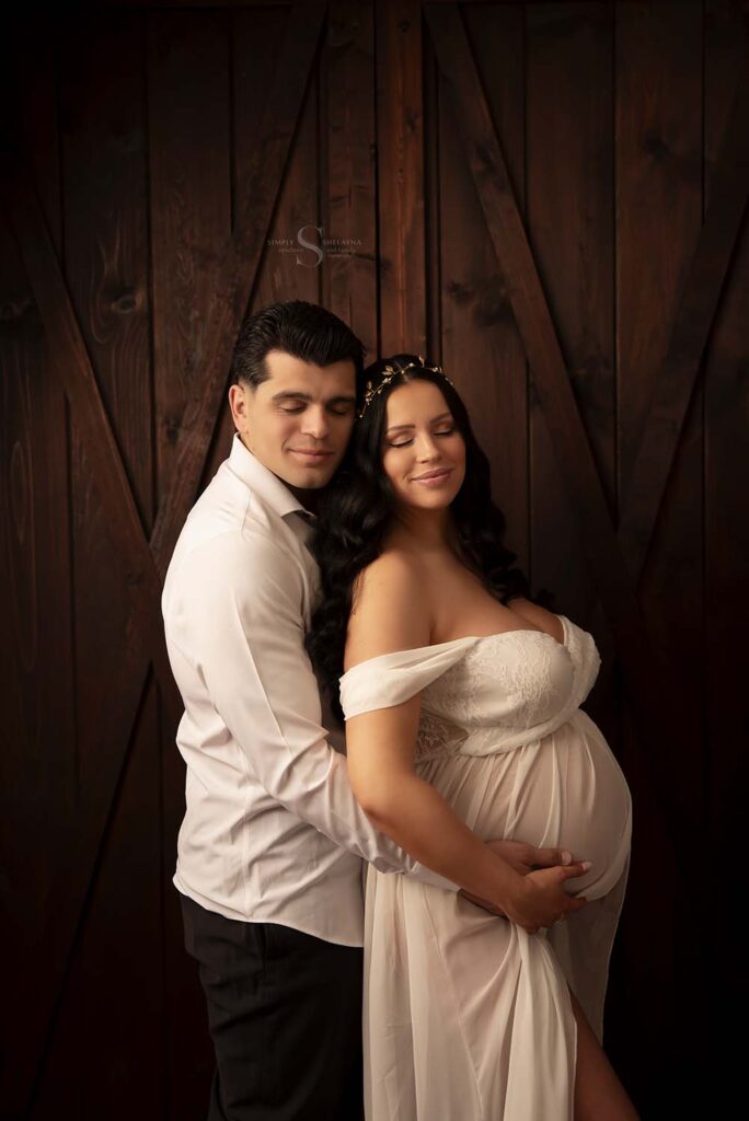 A couple hold each other close for a maternity portrait with Simply Shelayna Maternity Photography in Oswego NY.