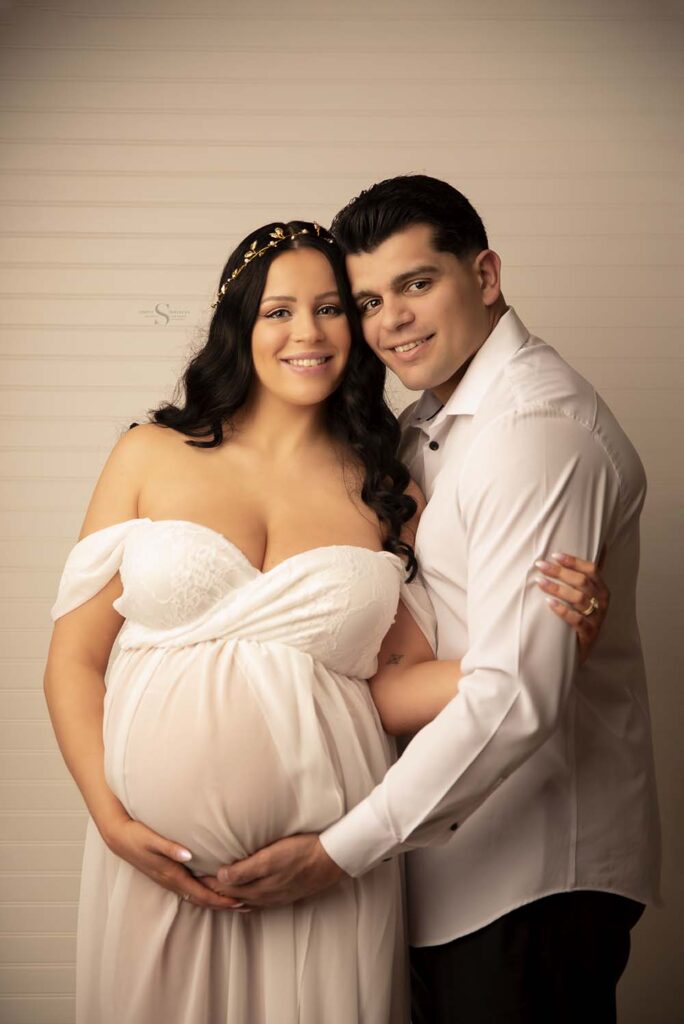 A couple hold each other close for a maternity portrait with Simply Shelayna Maternity Photography in Oswego NY.
