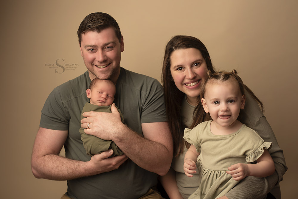 A family of four pose with their newborn son for a family portrait with Simply Shelayna family photographer in Syracuse NY.