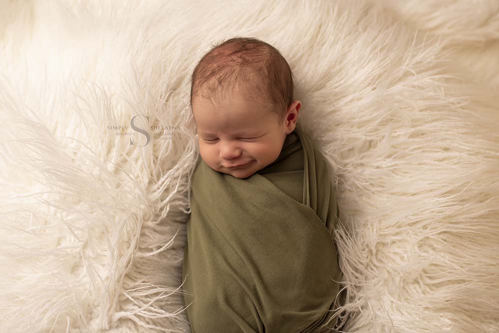 A newborn boy smirks for the camera with Simply Shelayna Newborn Photography in CNY.
