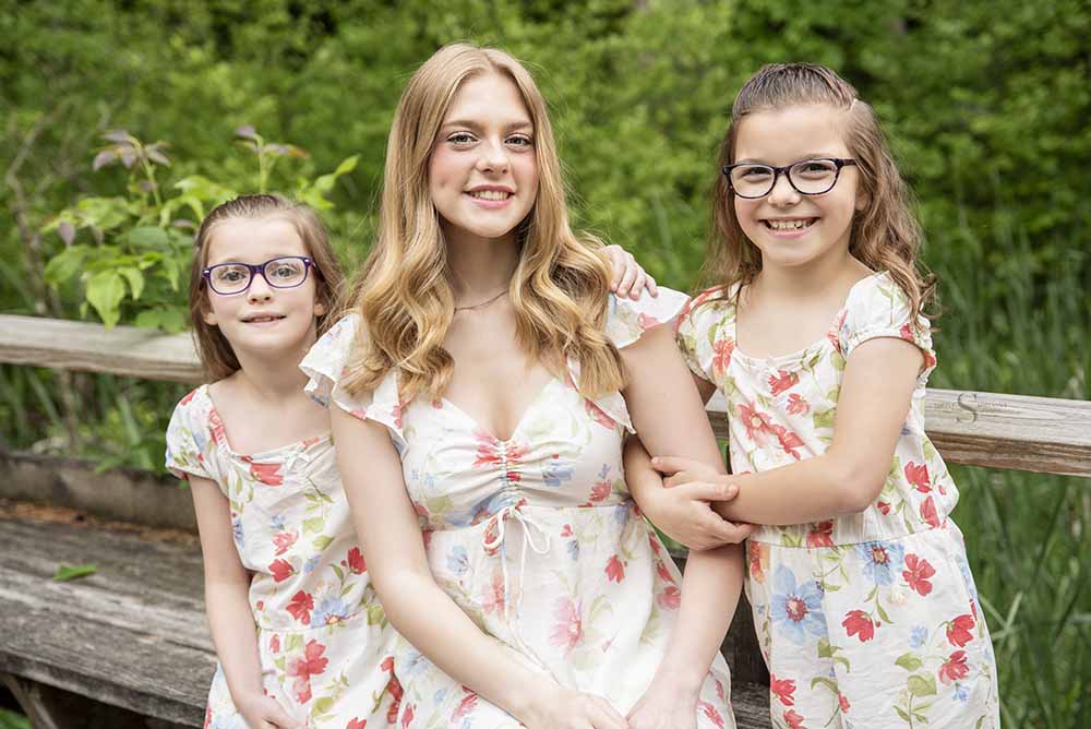 3 Sisters in matching floral outfits smile together for a portrait with Simply Shelayna Photography in Syracuse NY.