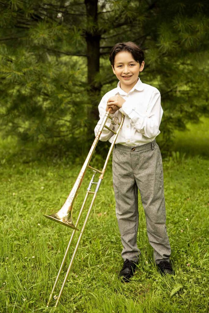 A young boy poses with his trombone with Simply Shelayna Child Photography in CNY.