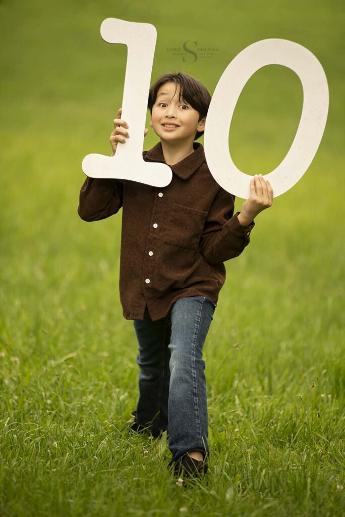 A ten year old boy poses with wooden digits to form a '10' to signify his age with Simply Shelayna Photography in CNY.