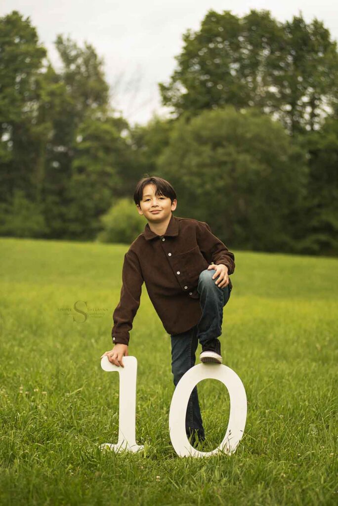 A ten year old boy poses with wooden digits to form a '10' to signify his age with Simply Shelayna Photography in CNY.