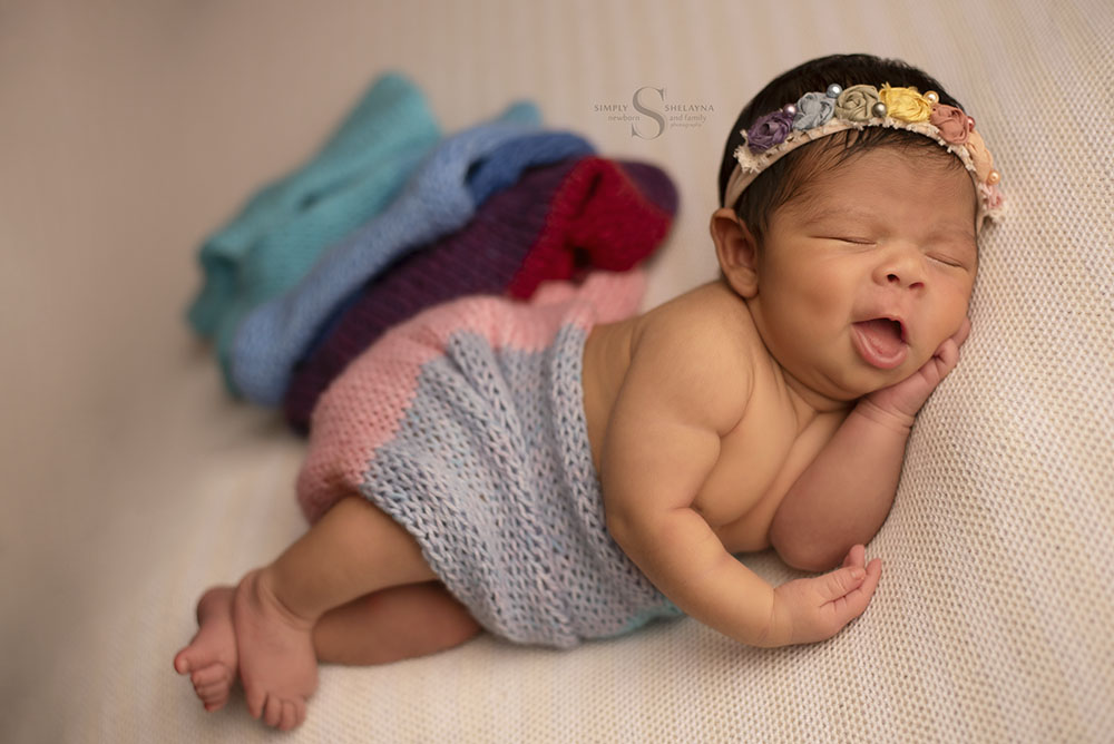 A newborn rainbow baby sleeps with a smile on her face with Simply Shelayna Newborn photography in CNY.