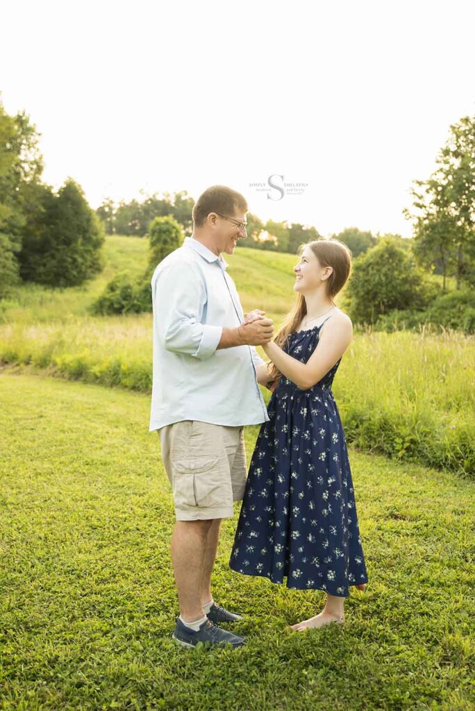A father dances with his teenage daughter in an open field with Simply Shelayna Family Photography in CNY.