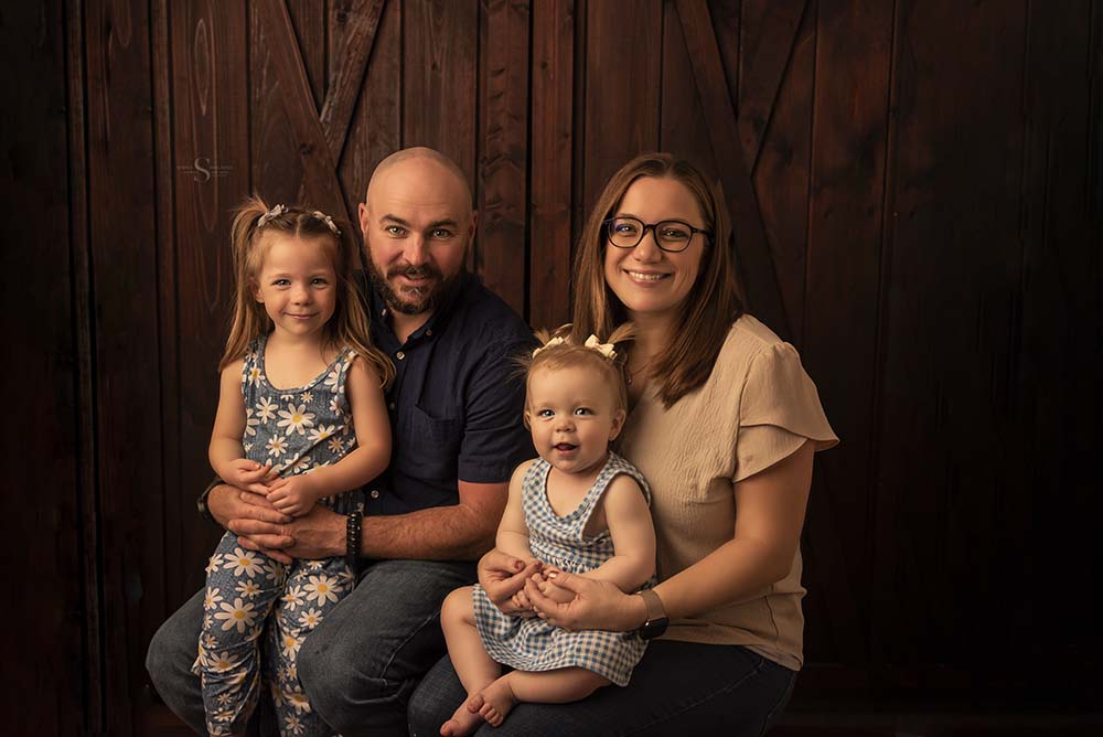 A family of 4 with 2 young daughters pose for a portrait with Simply Shelayna Family photography in Syracuse NY.