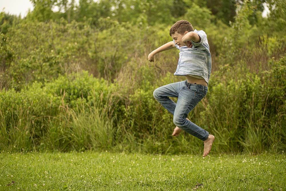 A young boy does a flying karate kick for a portrait with Simply Shelayna Photography in CNY.