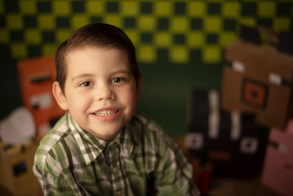 A five year old boy posing for a photo in a Minecraft setting with Simply Shelayna Child Photography in CNY.